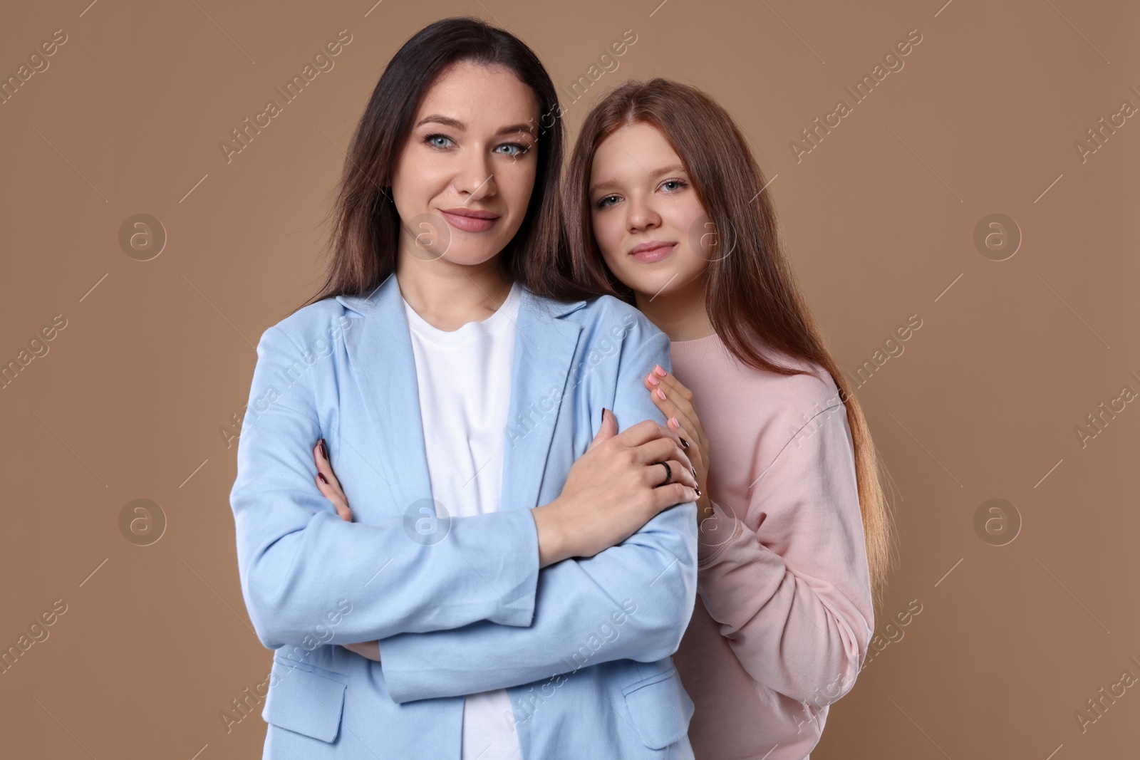 Photo of Portrait of beautiful mother with teenage daughter on dark beige background