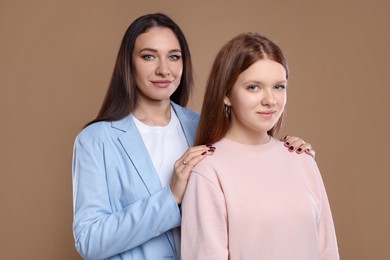 Photo of Portrait of beautiful mother with teenage daughter on dark beige background