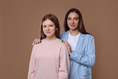 Photo of Portrait of beautiful mother with teenage daughter on dark beige background