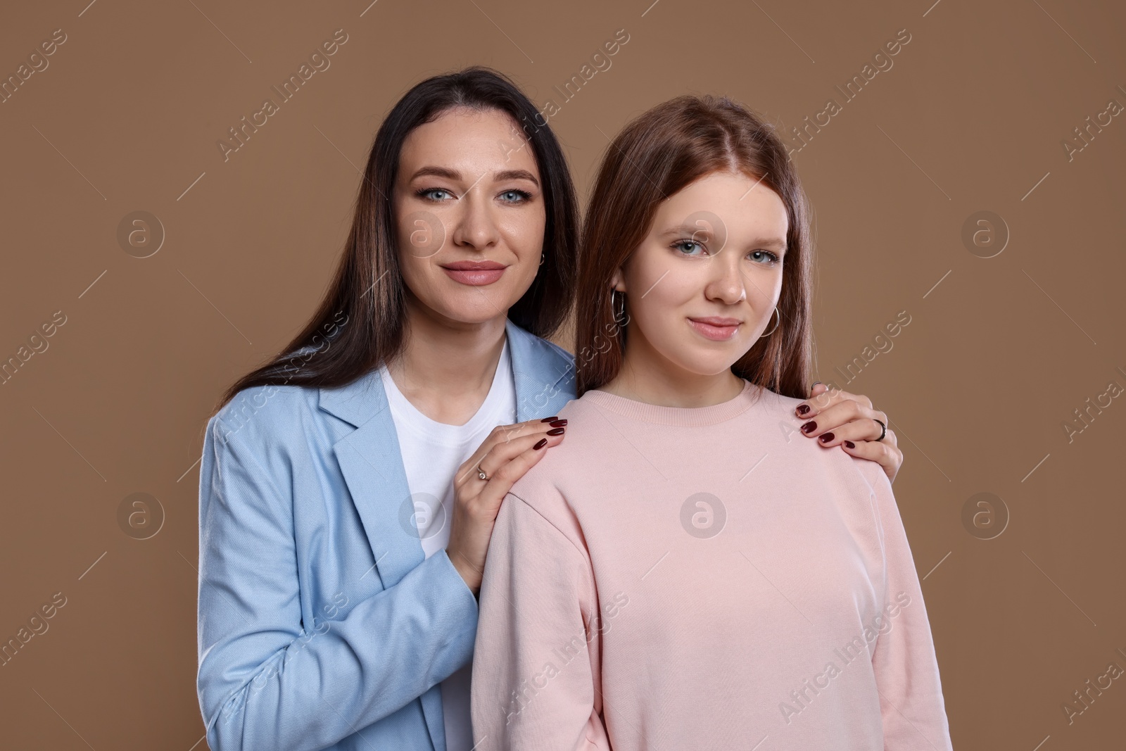 Photo of Portrait of beautiful mother with teenage daughter on dark beige background