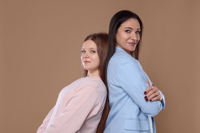 Photo of Portrait of beautiful mother with teenage daughter on dark beige background