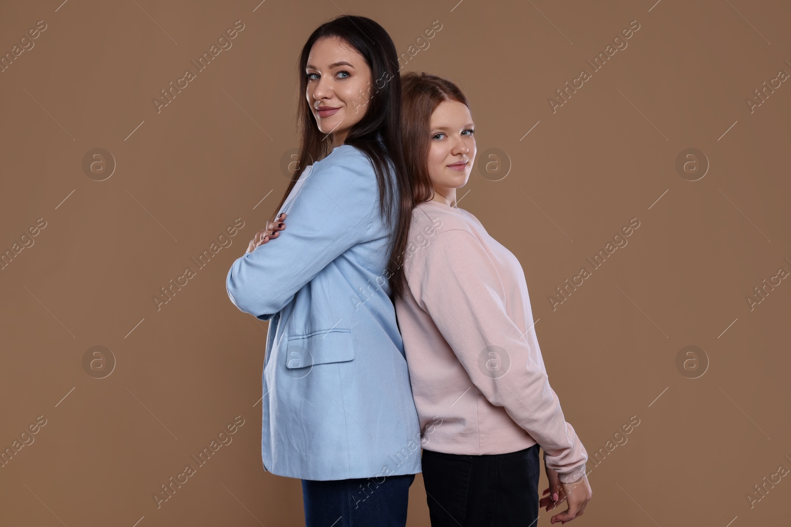 Photo of Portrait of beautiful mother with teenage daughter on dark beige background