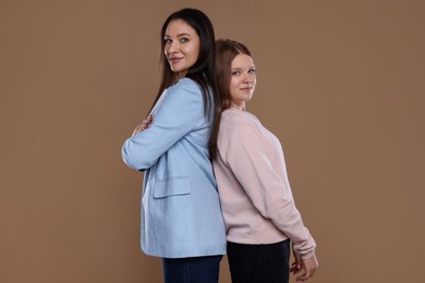 Photo of Portrait of beautiful mother with teenage daughter on dark beige background