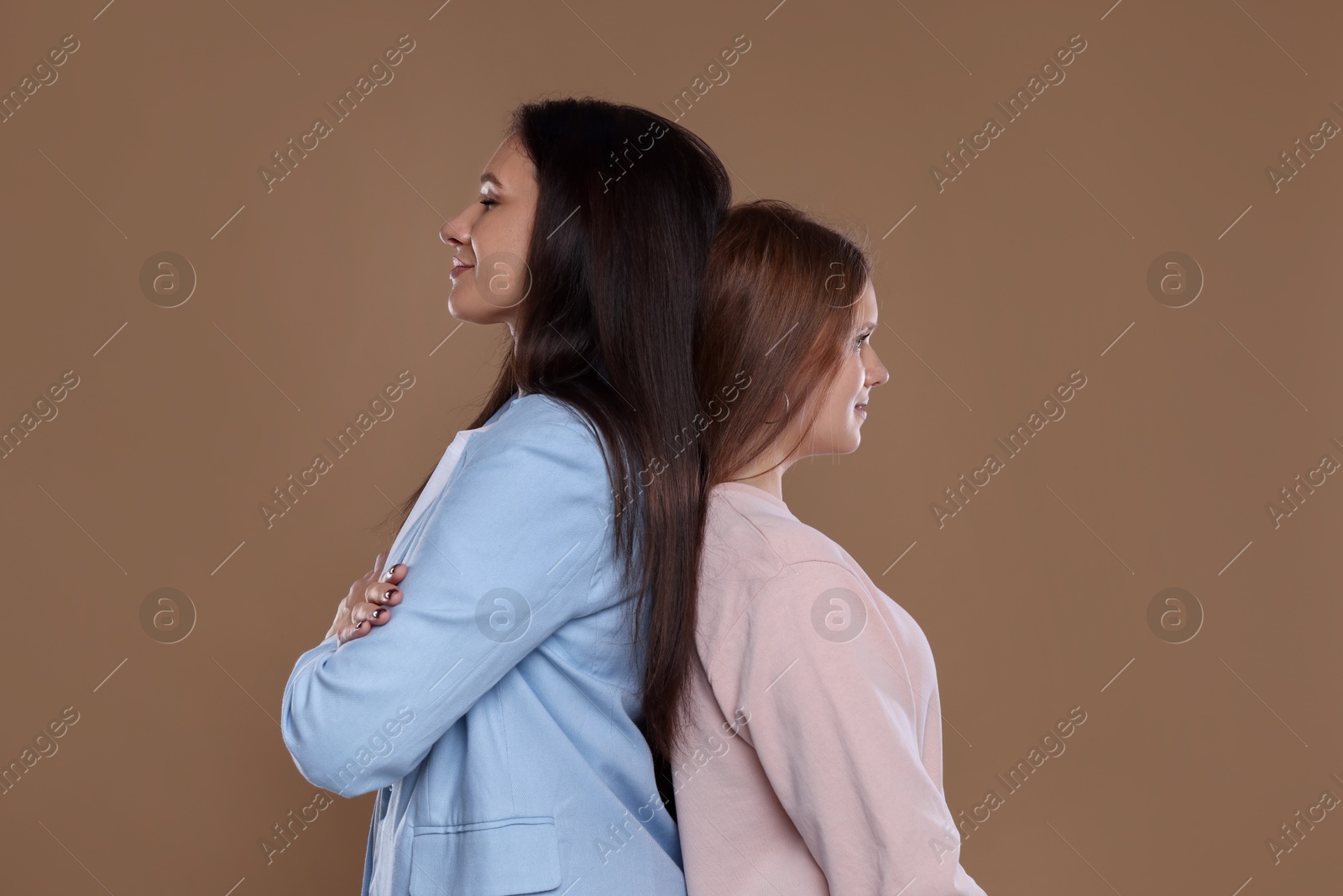 Photo of Portrait of beautiful mother with teenage daughter on dark beige background