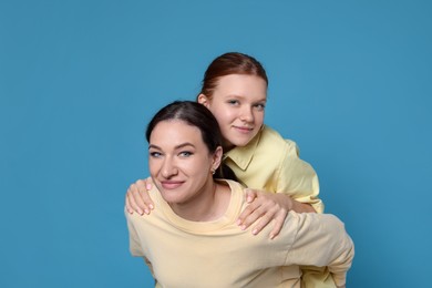 Photo of Portrait of beautiful mother with teenage daughter on light blue background