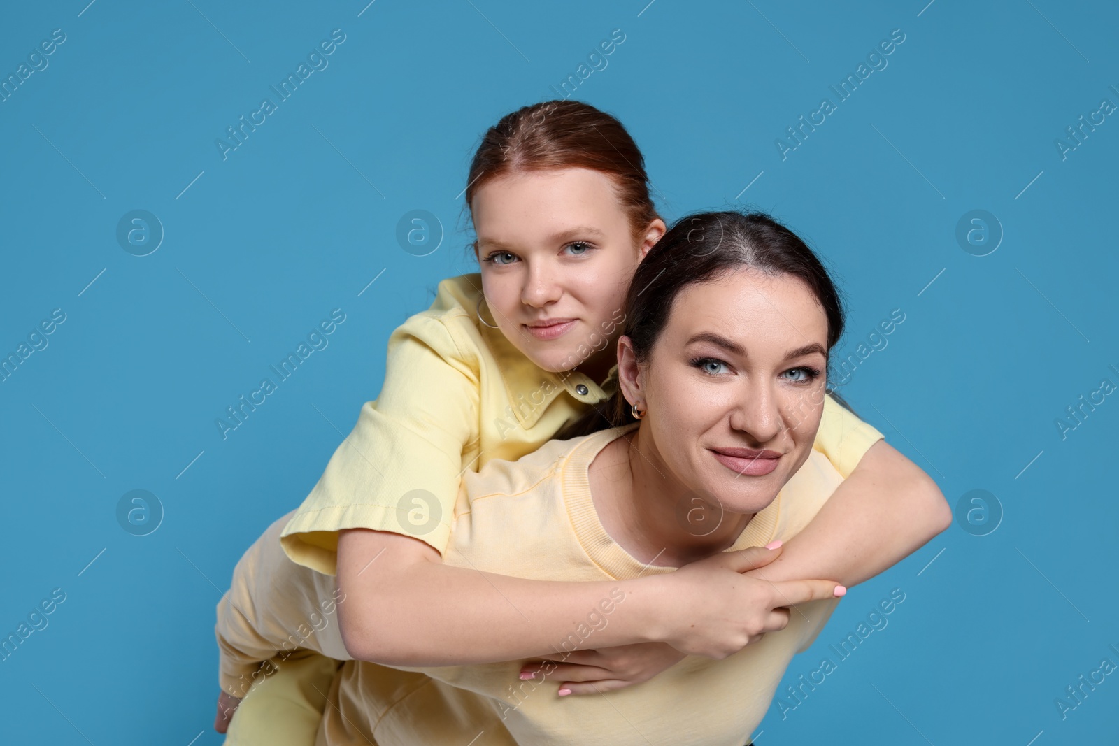 Photo of Portrait of beautiful mother with teenage daughter on light blue background