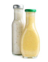 Photo of Different delicious sauces in glass bottles isolated on white