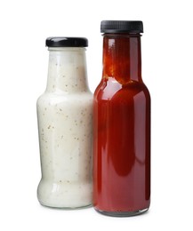 Photo of Different delicious sauces in glass bottles isolated on white