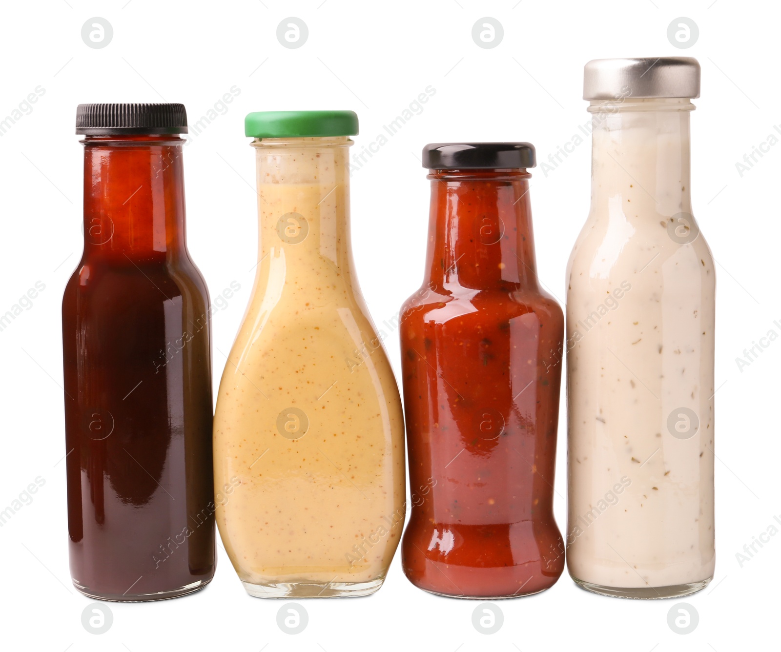 Photo of Different delicious sauces in glass bottles isolated on white