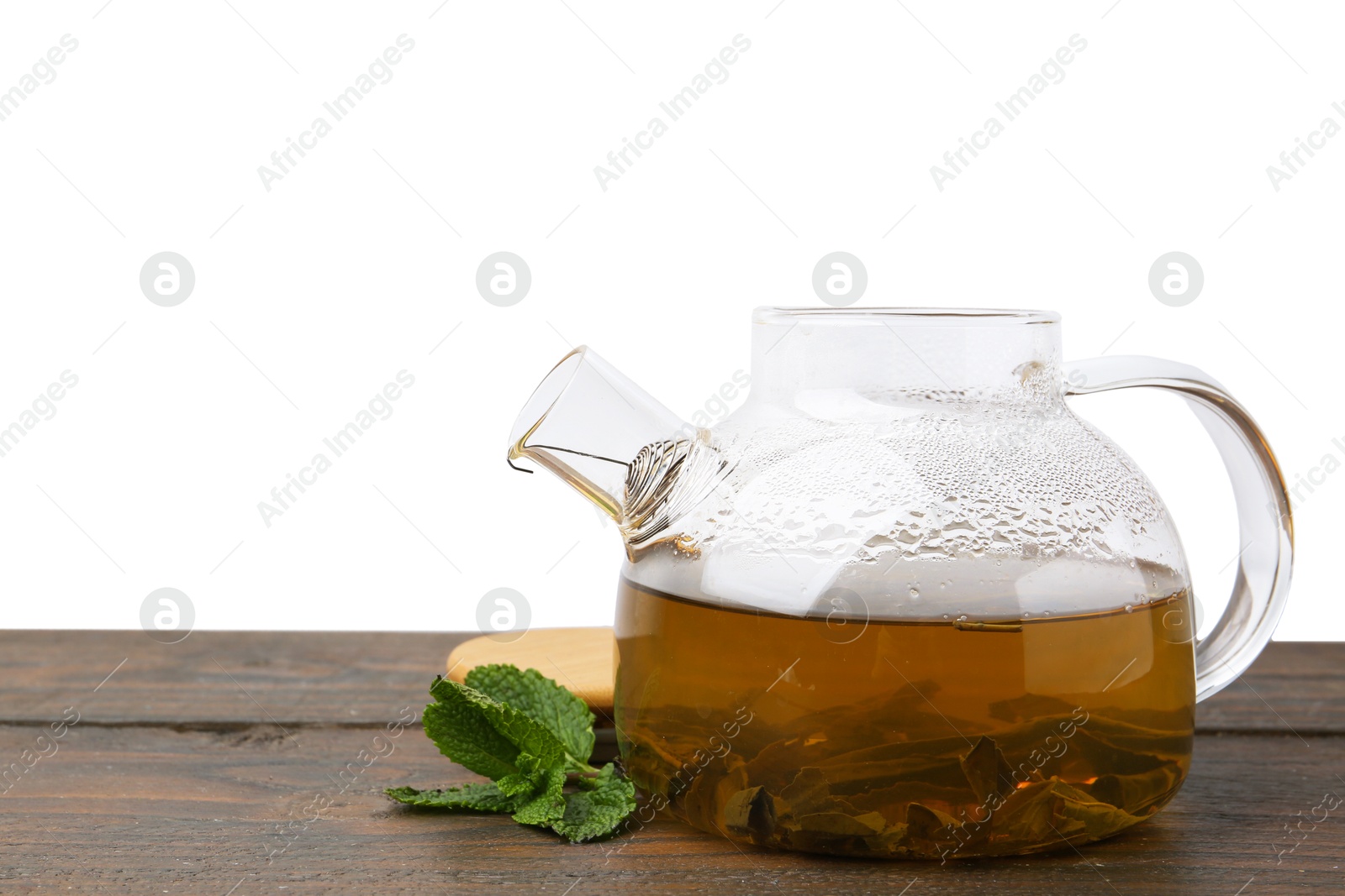 Photo of Aromatic mint tea in glass teapot and fresh leaves on wooden table against white background, space for text