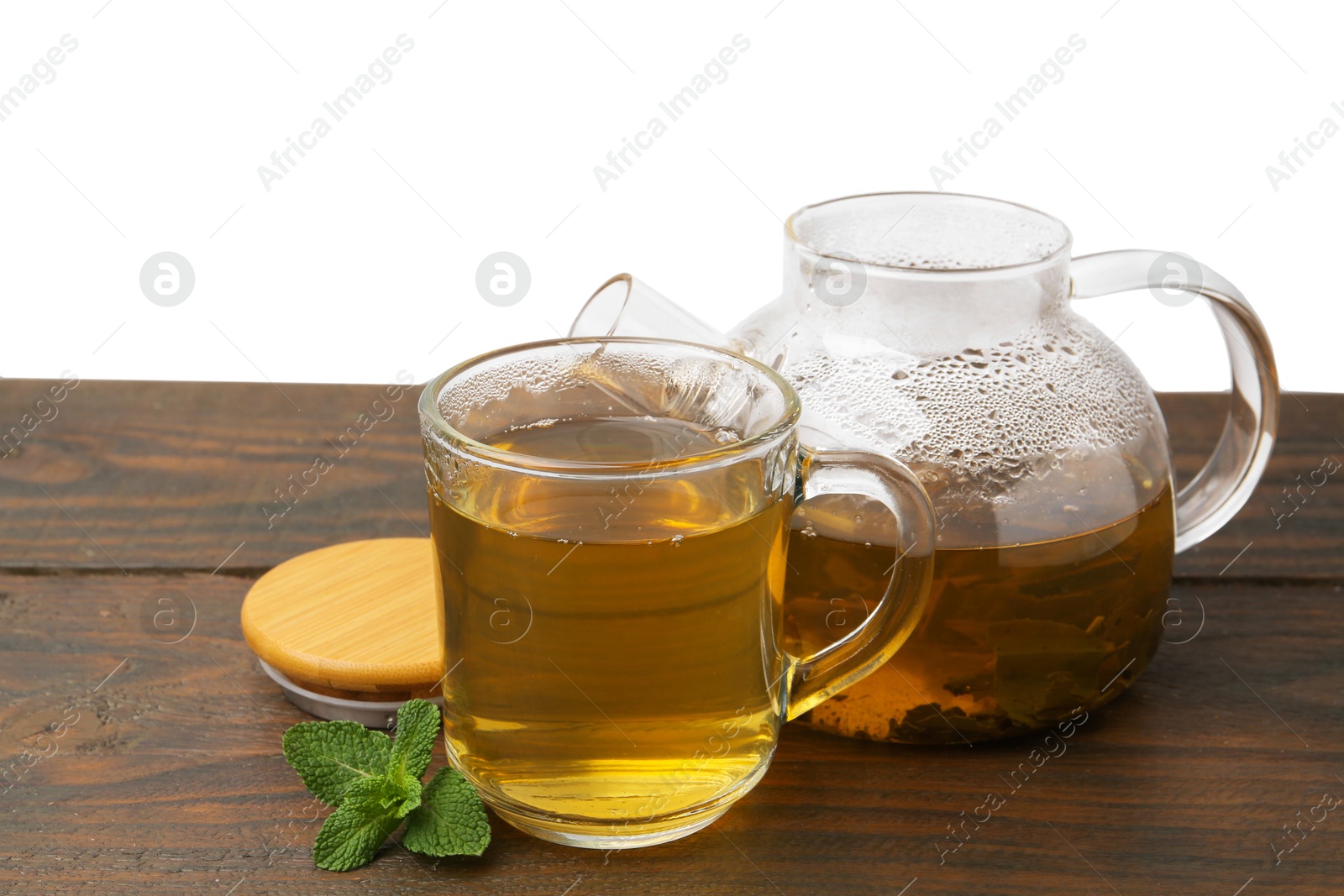 Photo of Aromatic mint tea and fresh leaves on wooden table against white background