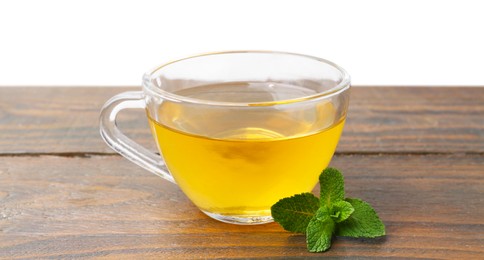 Photo of Aromatic mint tea in glass cup and fresh leaves on wooden table against white background