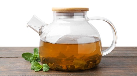 Photo of Aromatic mint tea in glass teapot and fresh leaves on wooden table against white background