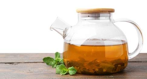 Photo of Aromatic mint tea in glass teapot and fresh leaves on wooden table against white background, space for text