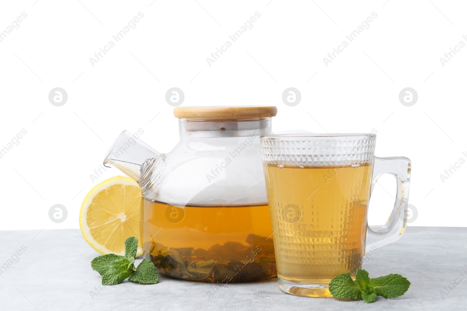 Photo of Aromatic mint tea, fresh leaves and lemon on light gray table against white background