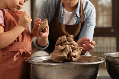 Photo of Hobby and craft. Mother with her daughter making pottery indoors, closeup