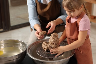 Photo of Hobby and craft. Mother with her daughter making pottery indoors, closeup