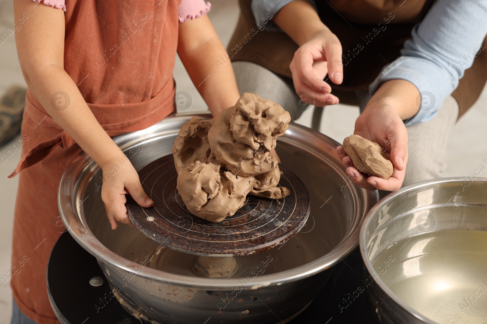 Photo of Hobby and craft. Mother with her daughter making pottery indoors, closeup