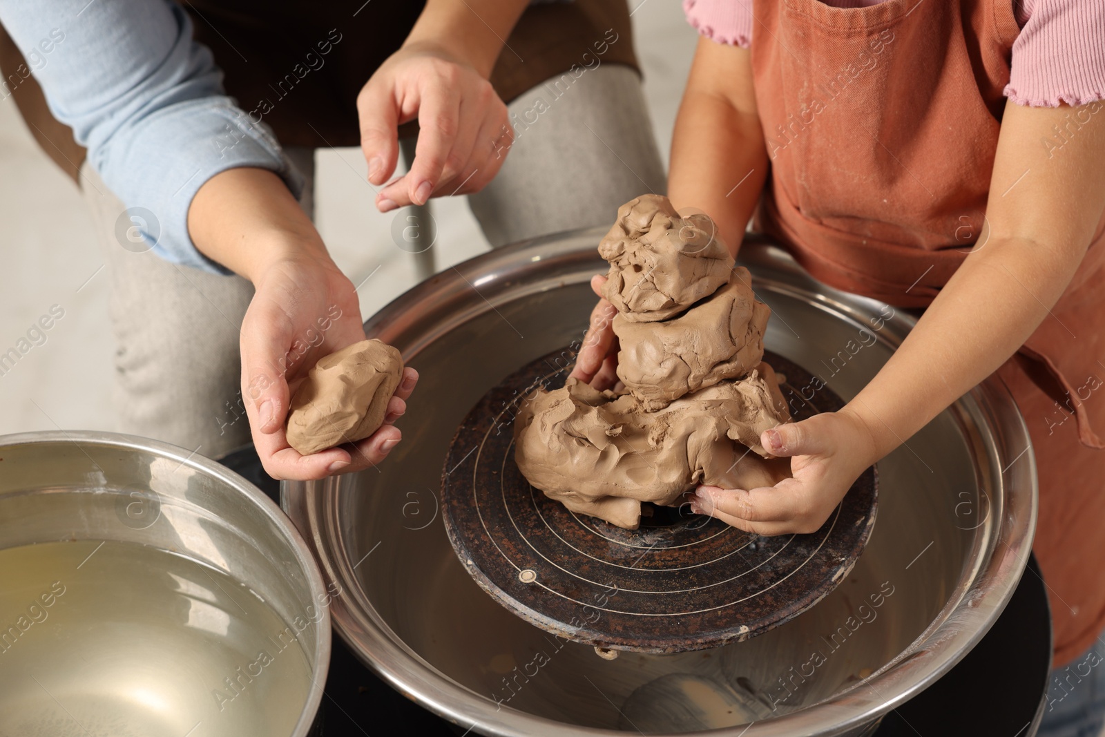 Photo of Hobby and craft. Mother with her daughter making pottery indoors, closeup