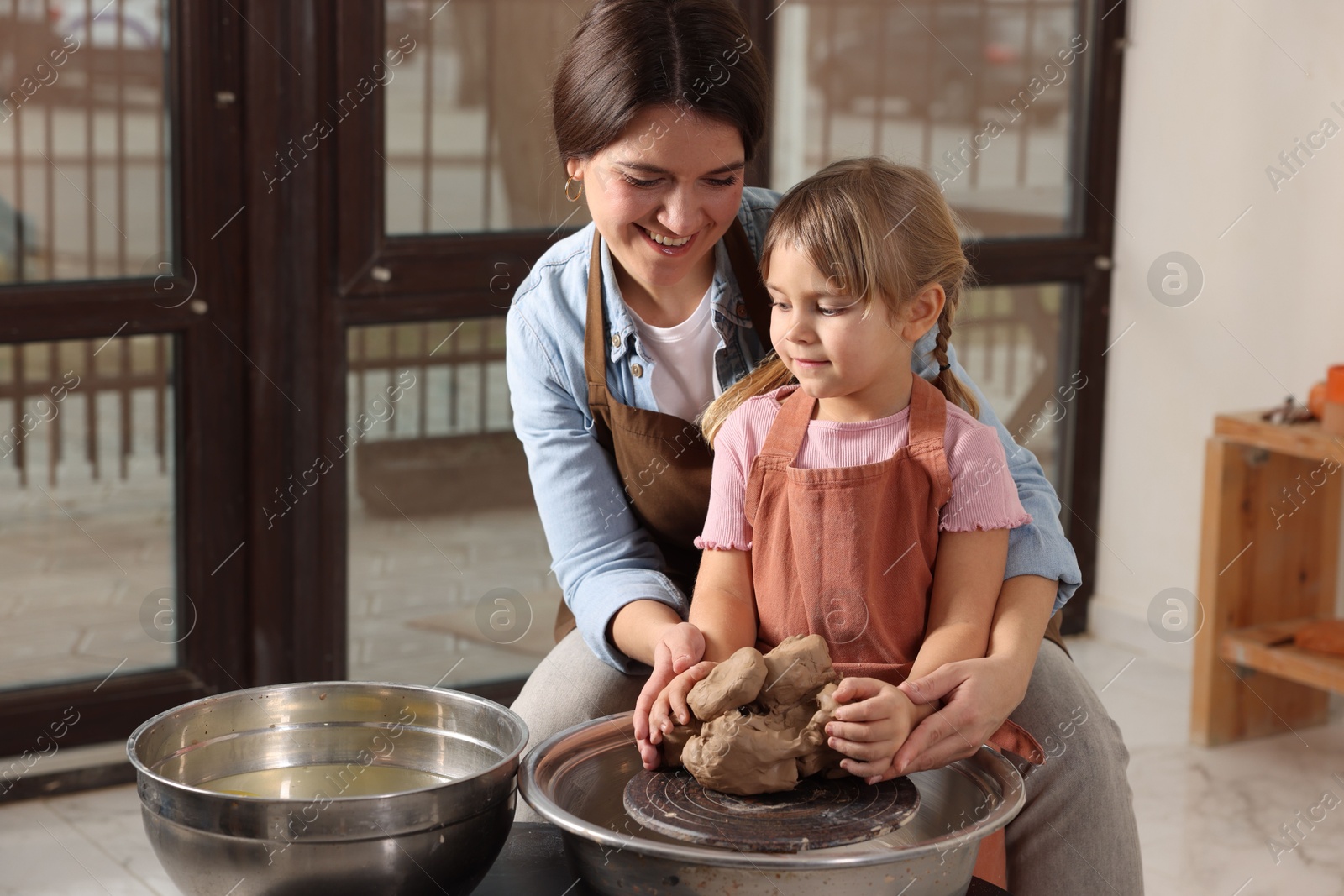 Photo of Hobby and craft. Smiling mother with her daughter making pottery indoors