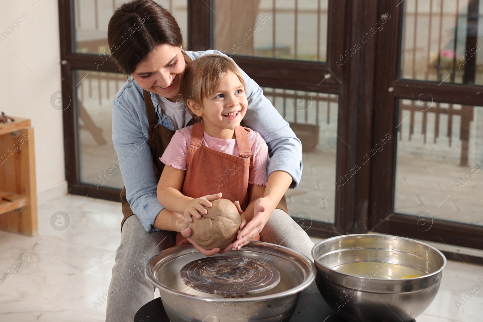 Photo of Hobby and craft. Smiling mother with her daughter making pottery indoors