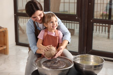 Photo of Hobby and craft. Smiling mother with her daughter making pottery indoors