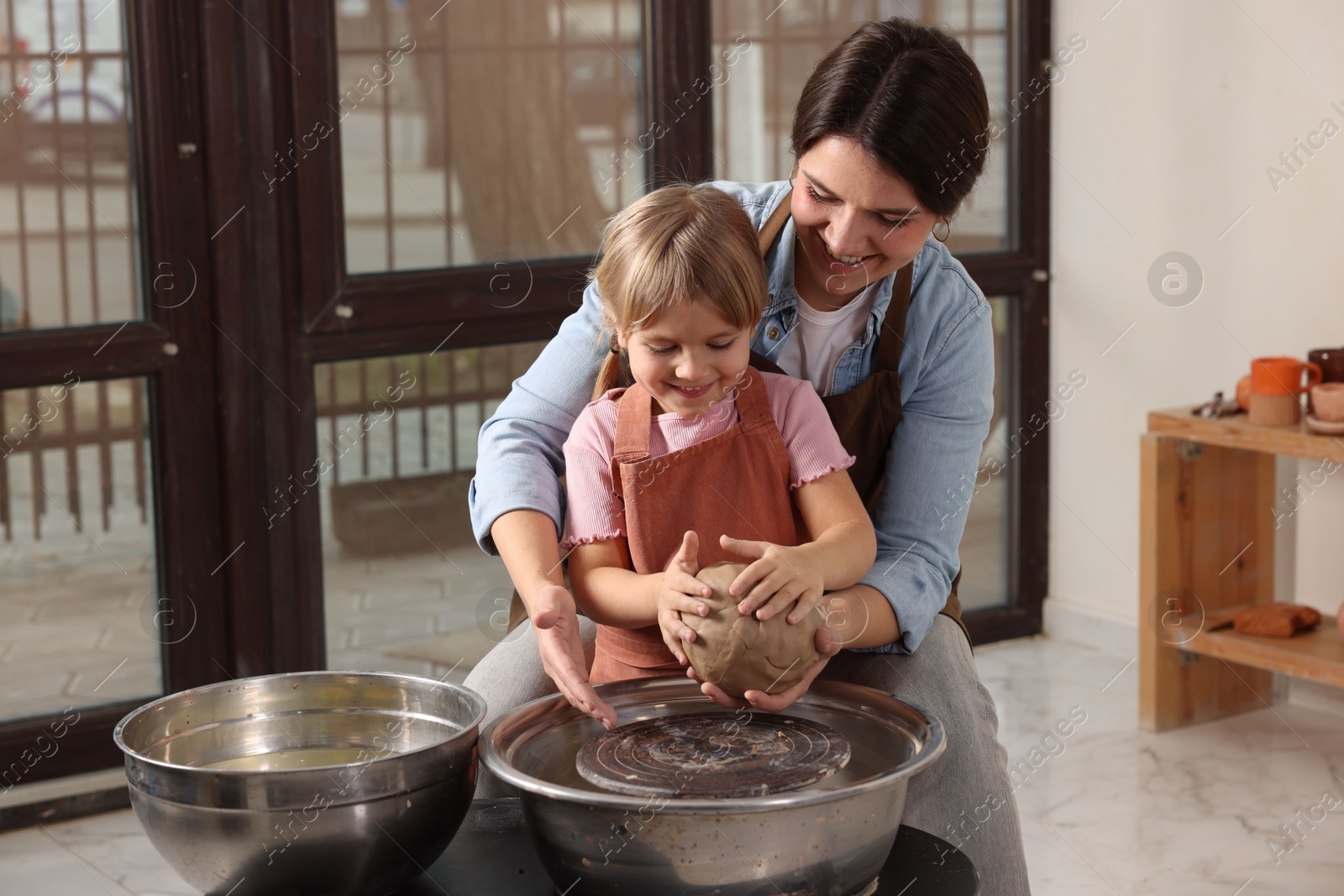 Photo of Hobby and craft. Smiling mother with her daughter making pottery indoors