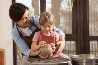 Photo of Hobby and craft. Smiling mother with her daughter making pottery indoors