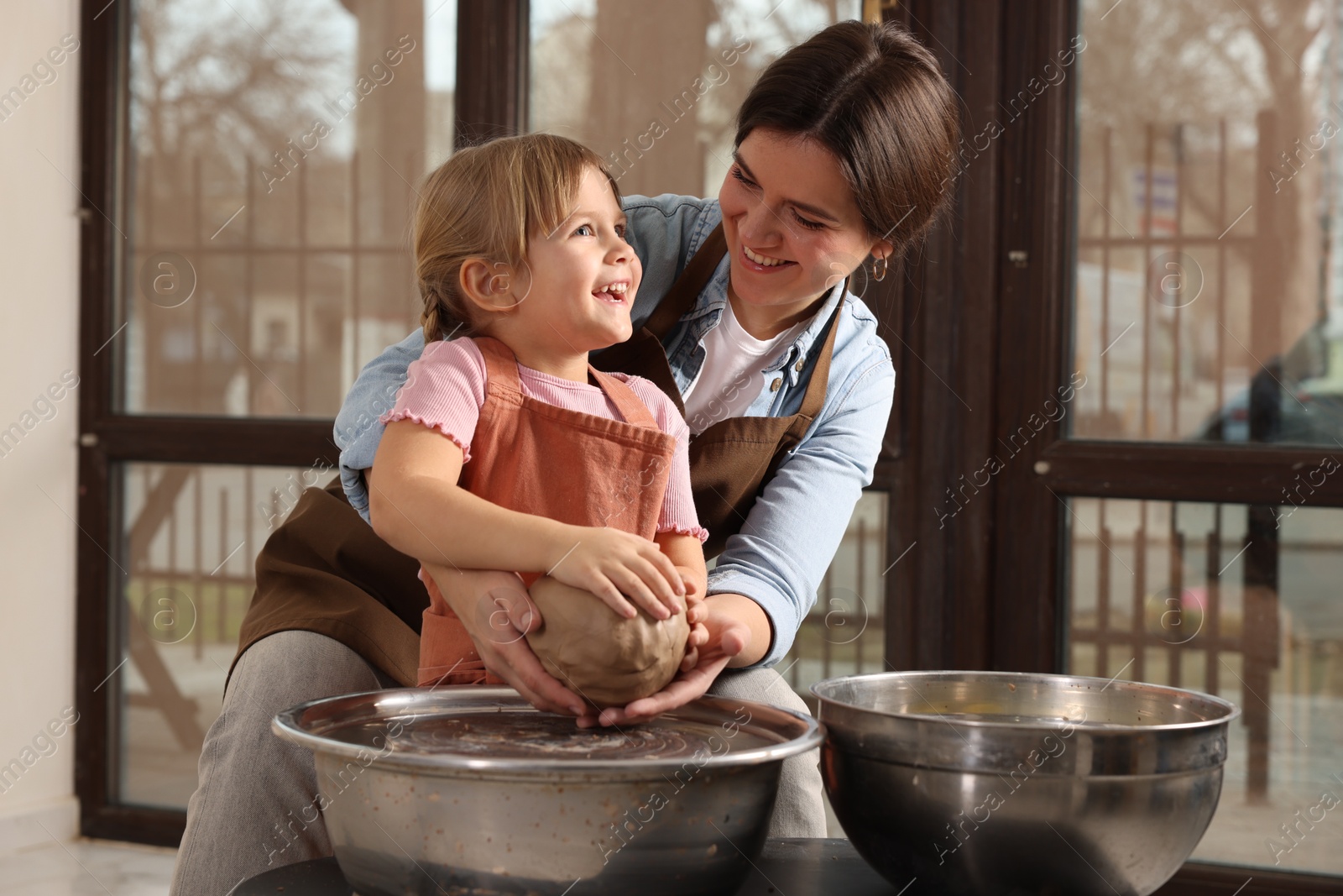 Photo of Hobby and craft. Smiling mother with her daughter making pottery indoors