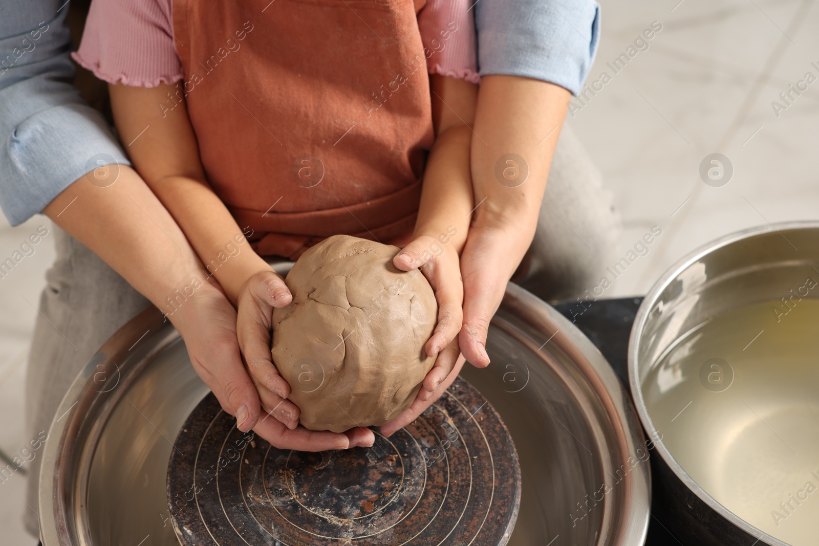 Photo of Hobby and craft. Mother with her daughter making pottery indoors, closeup