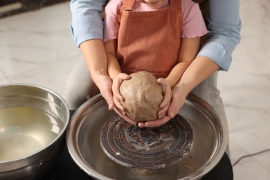 Photo of Hobby and craft. Mother with her daughter making pottery indoors, closeup