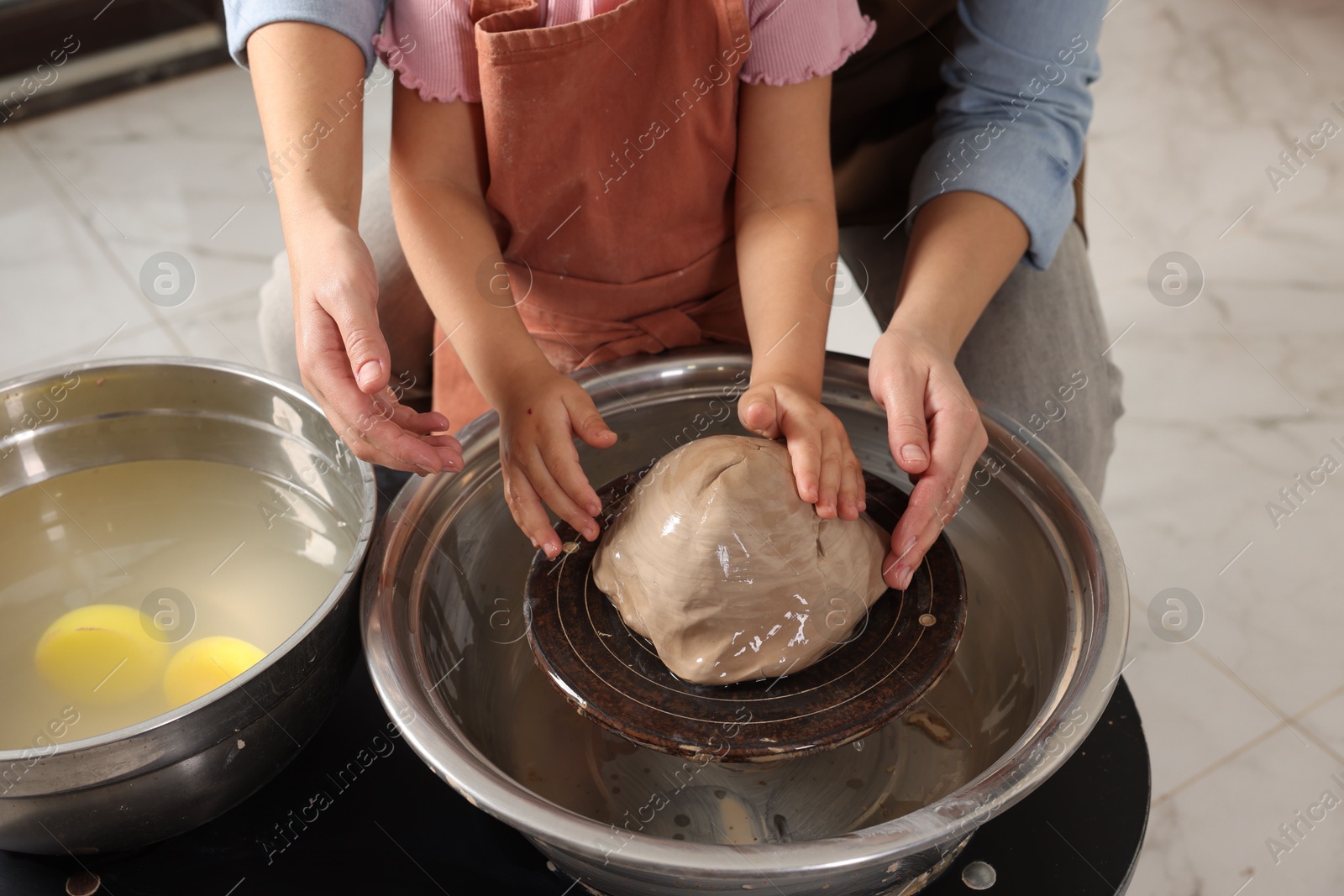 Photo of Hobby and craft. Mother with her daughter making pottery indoors, closeup