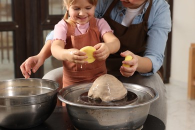 Photo of Hobby and craft. Mother with her daughter making pottery indoors, closeup