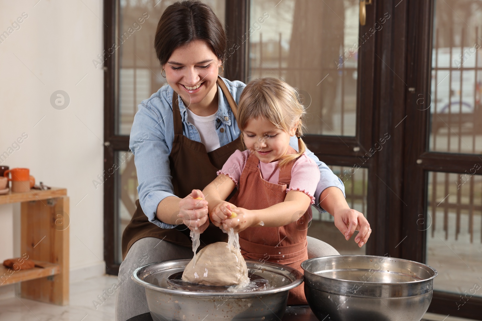 Photo of Hobby and craft. Smiling mother with her daughter making pottery indoors