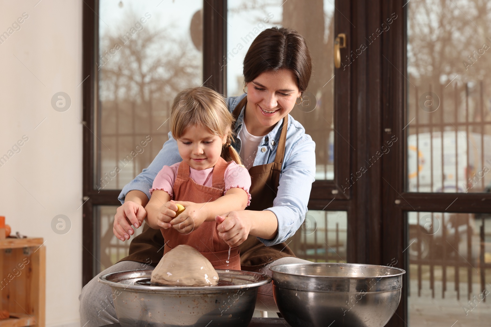 Photo of Hobby and craft. Smiling mother with her daughter making pottery indoors