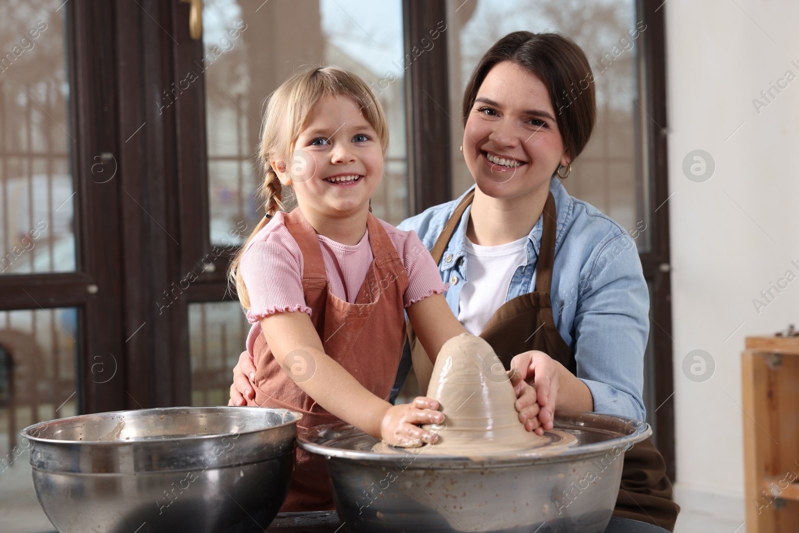 Photo of Hobby and craft. Smiling mother with her daughter making pottery indoors