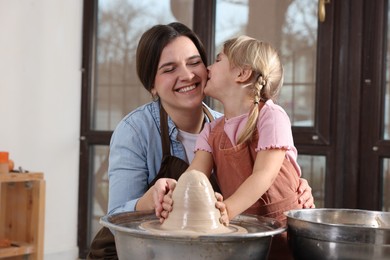 Photo of Hobby and craft. Smiling mother with her daughter making pottery indoors