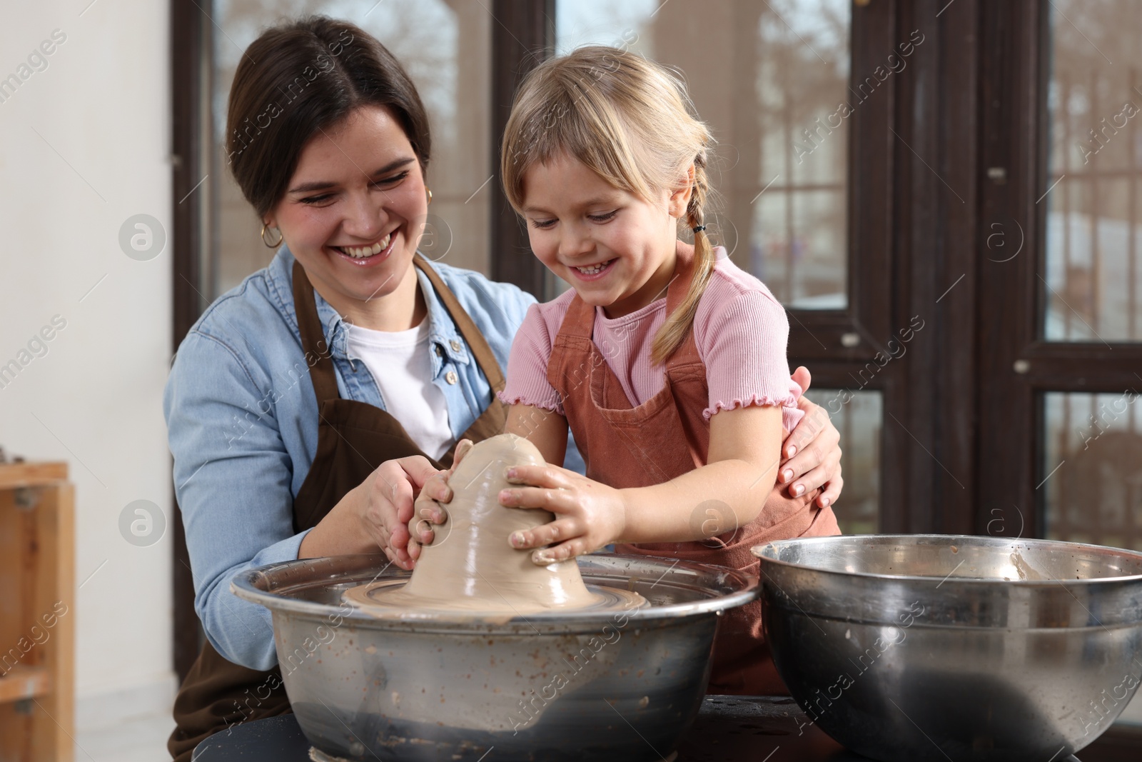 Photo of Hobby and craft. Smiling mother with her daughter making pottery indoors