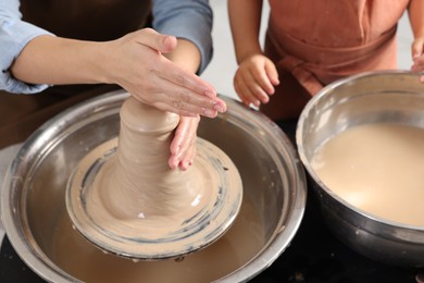 Photo of Hobby and craft. Mother with her daughter making pottery indoors, closeup