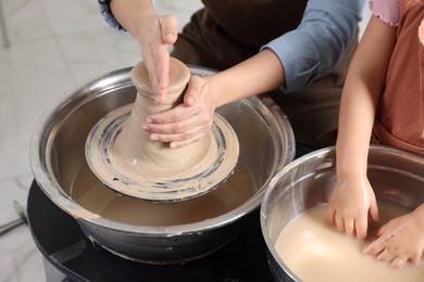 Photo of Hobby and craft. Mother with her daughter making pottery indoors, closeup