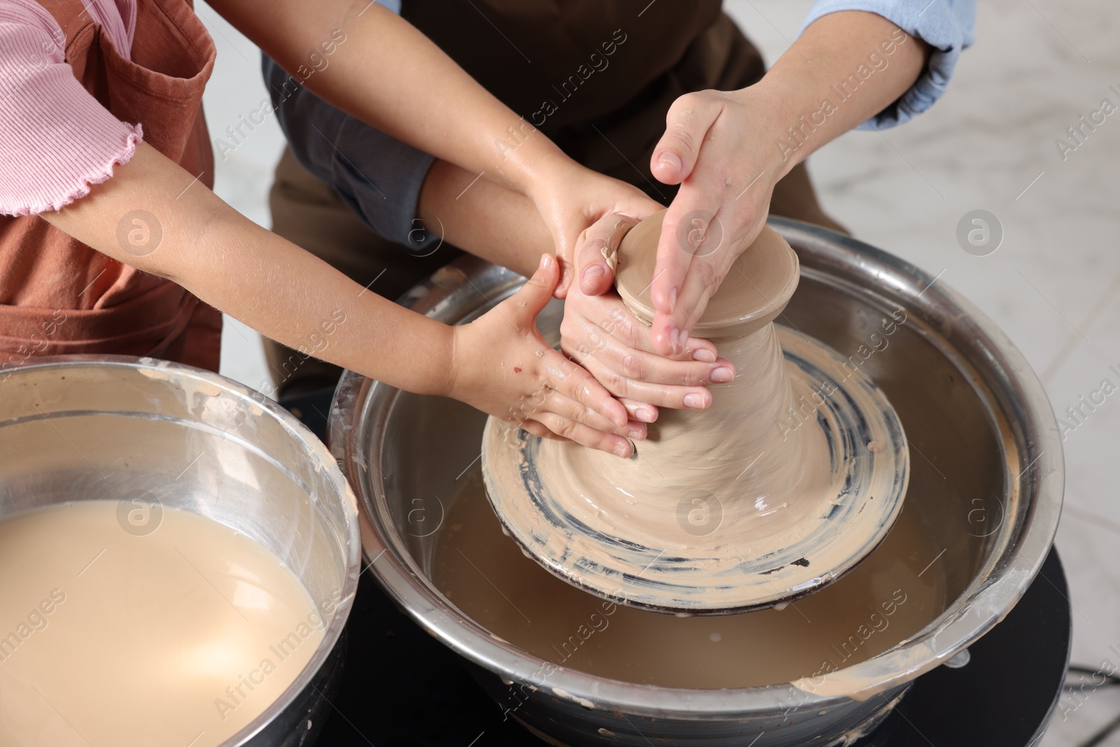 Photo of Hobby and craft. Mother with her daughter making pottery indoors, closeup