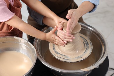 Photo of Hobby and craft. Mother with her daughter making pottery indoors, closeup