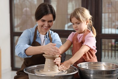 Photo of Hobby and craft. Smiling mother with her daughter making pottery indoors