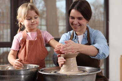 Photo of Hobby and craft. Smiling mother with her daughter making pottery indoors