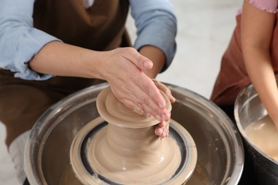 Photo of Hobby and craft. Mother with her daughter making pottery indoors, closeup