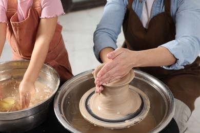 Photo of Hobby and craft. Mother with her daughter making pottery indoors, closeup