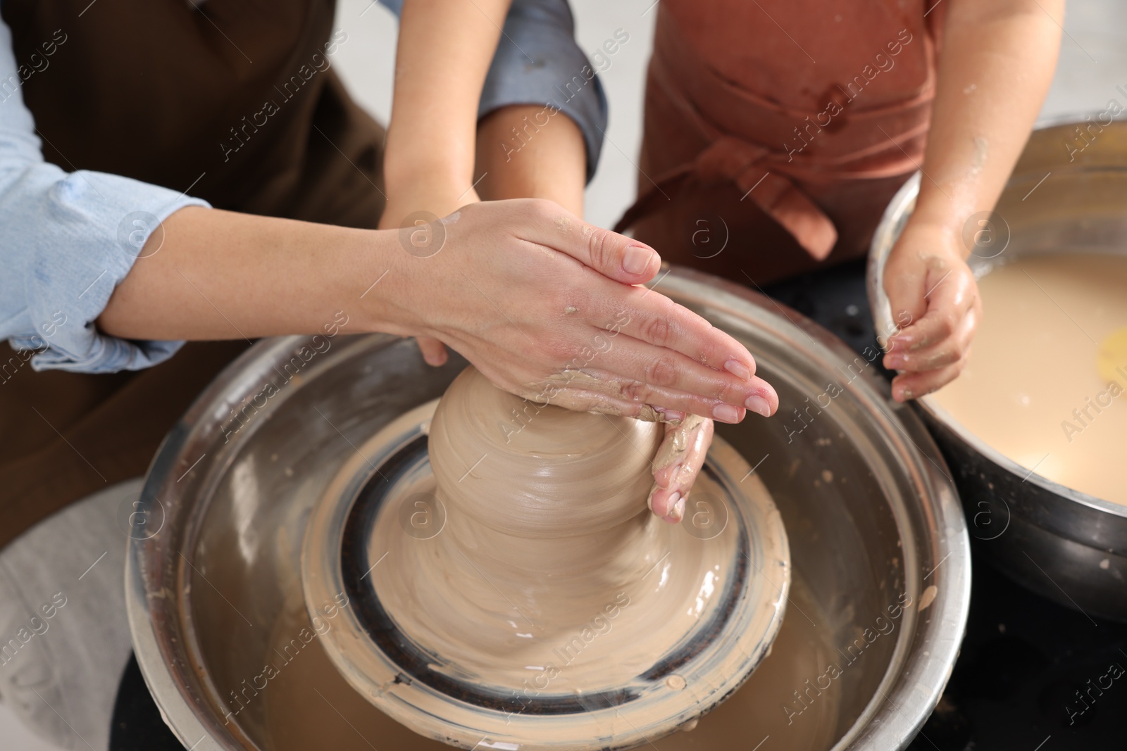 Photo of Hobby and craft. Mother with her daughter making pottery indoors, closeup