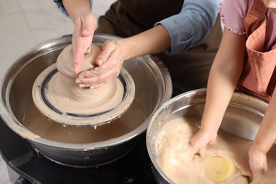 Photo of Hobby and craft. Mother with her daughter making pottery indoors, closeup