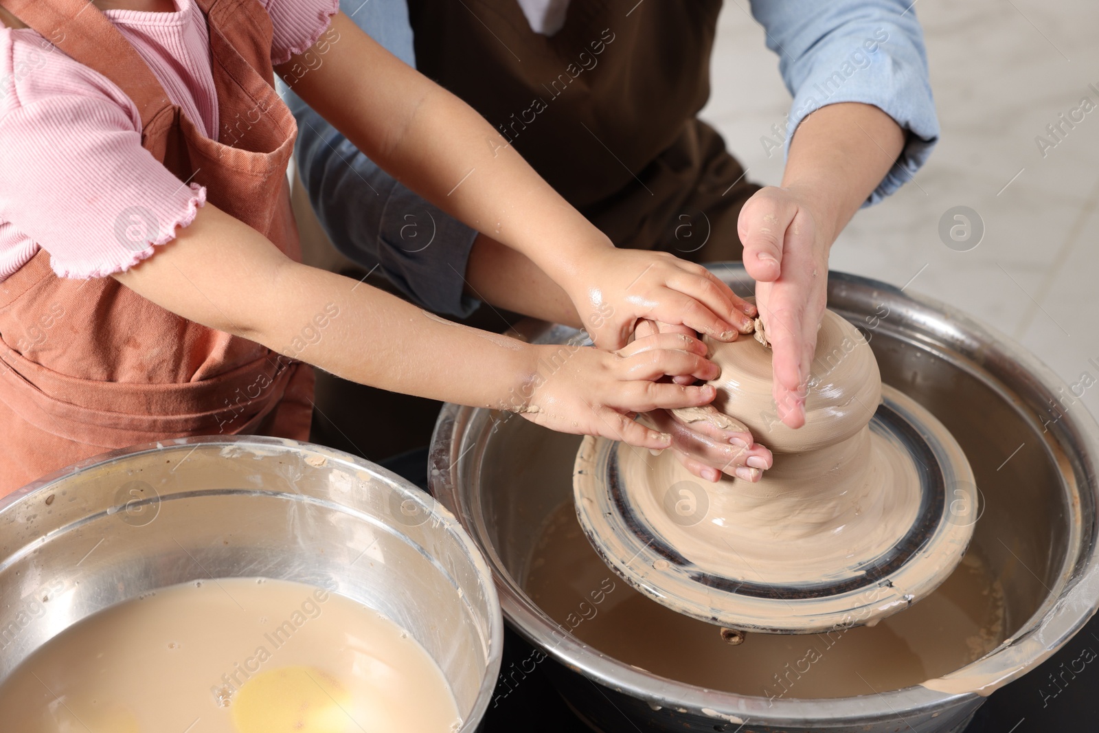 Photo of Hobby and craft. Mother with her daughter making pottery indoors, closeup