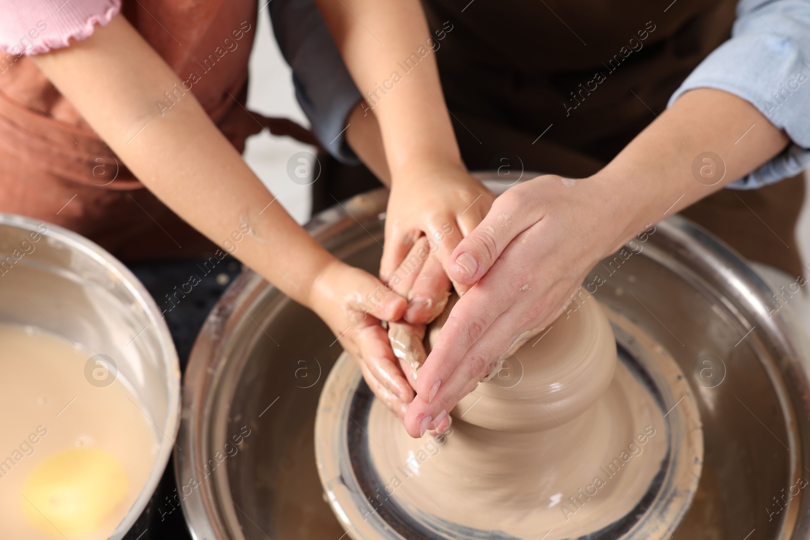 Photo of Hobby and craft. Mother with her daughter making pottery indoors, closeup